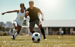 Man and a Woman on a soccer field competing for the ball