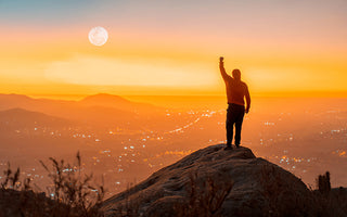 Man on Top of Mountain looking over city at sunset