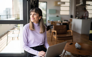 Woman with laptop in lap gazing outside