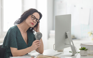 Woman at desk with holding a hand fan