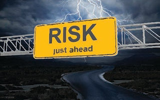 Overhead road sign displaying RISK on a stormy night