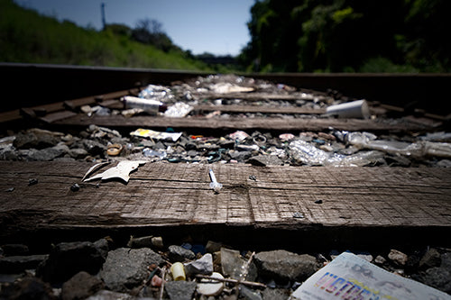 Run down railroad tracks with litter