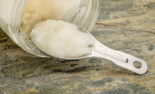 MCT Oil in a spoon in front of a jar of the same