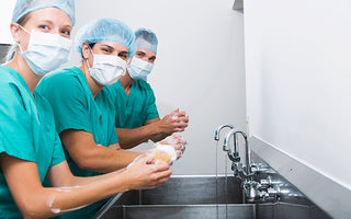 Three nurses scrubbing up for surgery
