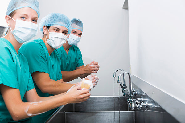 Three nurses scrubbing up for surgery